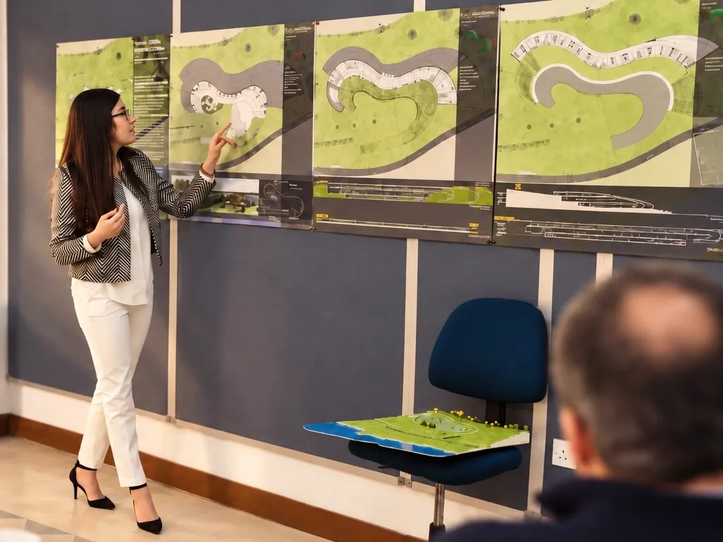 Presenting site plans and a physical model to a review panel at architecture school.